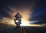 Motorkerékpáros naplemente az egyenes úton